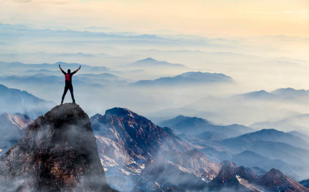 Success Young man enjoys success on top of a cliff mountain climbing photos stock pictures, royalty-free photos & images