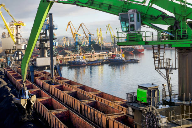 Balanced Hydraulic Crane - The manipulator unloads bulk cargo from industrial wagons in the seaport. stock photo
