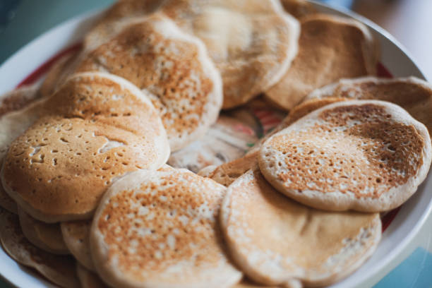 Two pancakes with butter on a plate on a wooden table.
