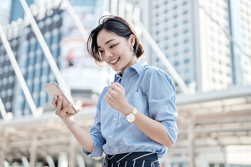 Una hermosa mujer de negocios asiática está mirando su teléfono inteligente y muy feliz. photo