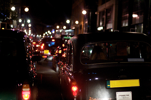 A close up image of a the back side of a black cab in traffic at night driving down the busy Broad street area of Birmingham, July 2009.