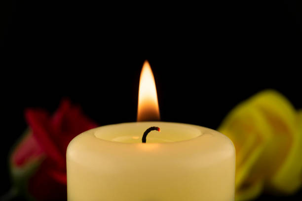 istock Burning yellow wax candle and two roses 1224019647