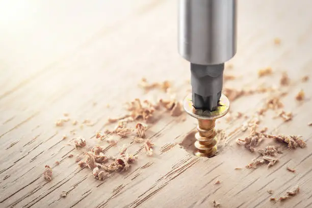 Photo of screwdriver screw in a wood oaks plank