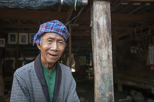 Yandabo Myanmar - October 28 2013; One senior man standing and smiling under shelter of his home well dressed in remote village.