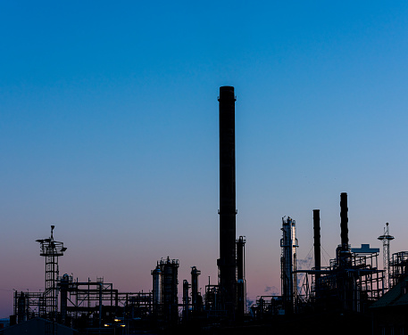Silhouettes of chimneys, pipes and other equipment at an oil refinery..