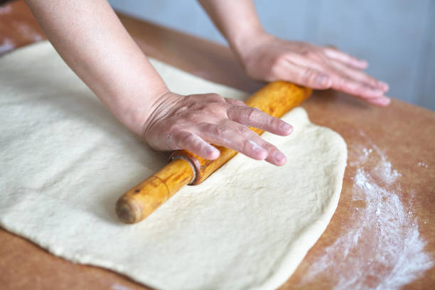 istock Women's hands roll the dough on the kitchen table. Women's hands with rolling pin 1224032725