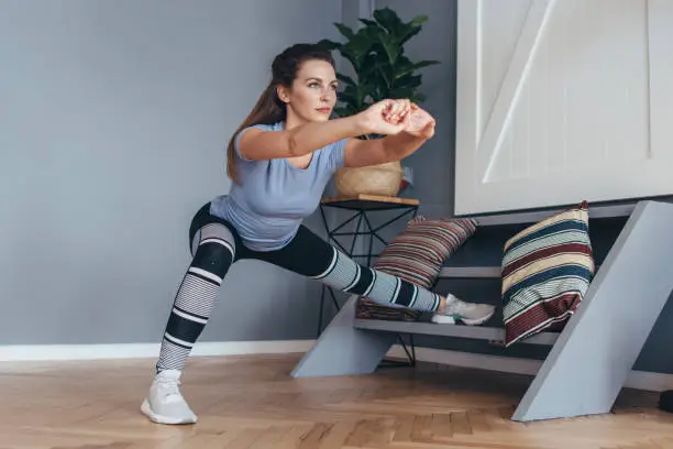 Photo of Fit woman stretching legs Lateral Lunge exercise.