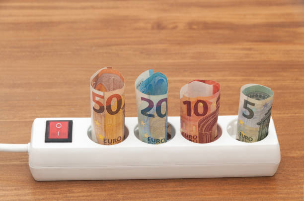 istock Euro banknotes inserted into an extension socket on a wooden surface. Expensive concepts of energy and cost of electricity. Front view. 1224033741