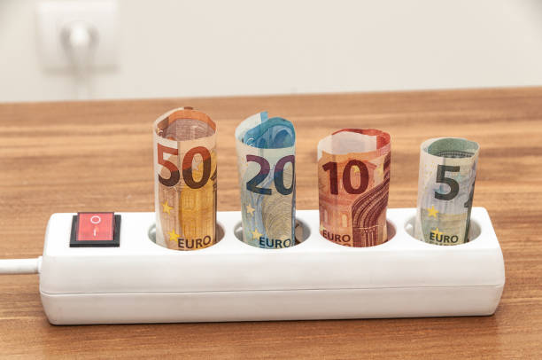 istock Euro banknotes inserted into an extension socket on a wooden surface. Expensive concepts of energy and cost of electricity. Front view. 1224033759