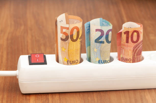 istock Euro banknotes inserted into an extension socket on a wooden surface. Expensive concepts of energy and cost of electricity. Front view. 1224033771