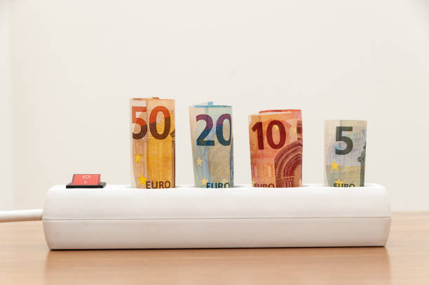 istock Euro banknotes inserted into an extension socket on a wooden surface. Expensive concepts of energy and cost of electricity. Front view. 1224033785