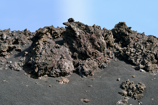 Volcany rocks on black lava under a blue sky