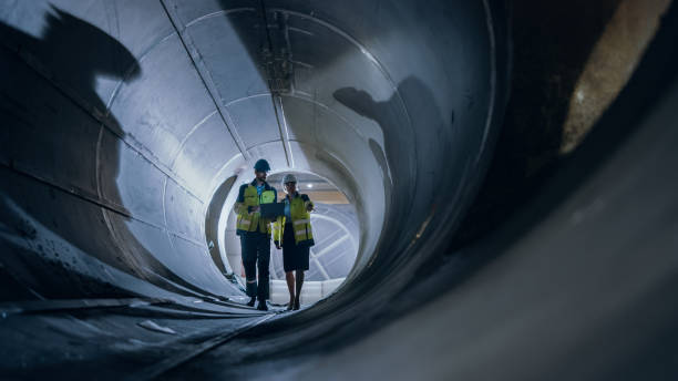 istock Two Heavy Industry Engineers Walking Inside Pipe, Use Laptop, Have Discussion, Checking Welding. Construction of the Oil, Natural Gas and fuels Transport Pipeline. Industrial Manufacturing Factory 1224034039