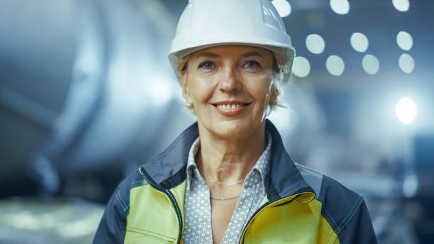 портрет профессиональной тяжелой промышленности женщина-инженер носить форму безопасности и жесткий шляпу, улыбаясь очаровательно. на за� - charmingly стоковые фото и изображения