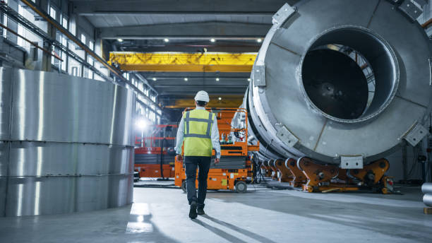 dopo lo scatto di ingegneri dell'industria pesante che camminano attraverso la fabbrica di produzione. in background professionisti che lavorano alla costruzione di prodotti per il trasporto di petrolio, gas e gasdotti - oil production foto e immagini stock