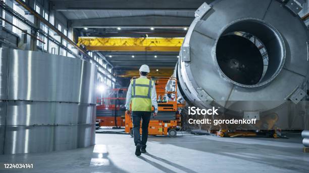 Following Shot Of Heavy Industry Engineers Walking Through Manufacturing Factory In The Background Professionals Working On Construction Of Oil Gas And Fuel Pipeline Transportation Products Stock Photo - Download Image Now