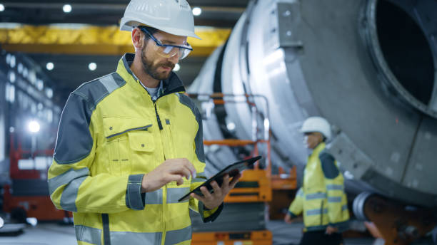 Heavy Industry Engineer Stands in Pipe Manufacturing Factory, Use Digital Tablet Computer. Facility for Construction of Oil, Gas and Fuel Pipeline Transportation Products. Heavy Industry Engineer Stands in Pipe Manufacturing Factory, Use Digital Tablet Computer. Facility for Construction of Oil, Gas and Fuel Pipeline Transportation Products. crude oil photos stock pictures, royalty-free photos & images