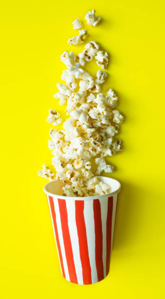 istock Paper Cup with drawn red stripes and scattered popcorn 1224034904