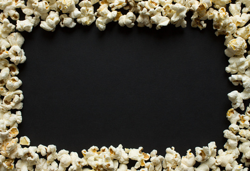 Frame-popcorn scattered on a black background close-up and copy space