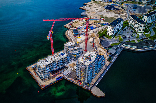 Aerial view of Construction site at Tuborg Havn and Svanemøllen in Copenhagen, Denmark. HDR imaging with cranes, contemporary homes and office buildings at the sea and harbour front.