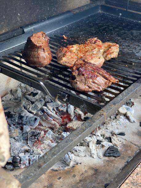 meat steaks fried on a black grid and charcoal