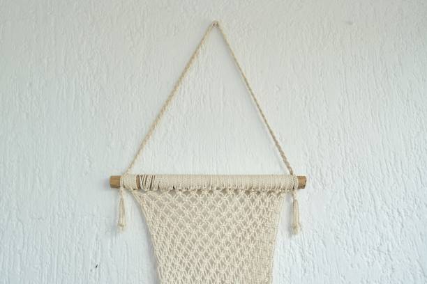 Handmade macrame, decorative panel woven from light cotton ropes on the wall