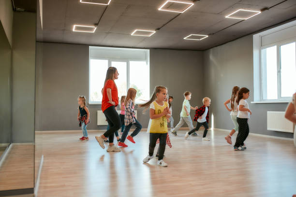 istock Learning dance figures with teacher. Group of little boys and girls dancing while having choreography class in the dance studio. Female dance teacher and children 1224039905