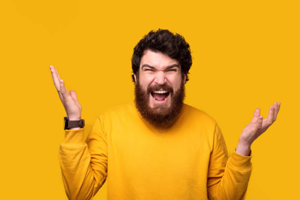 istock Bearded man is saying what, with hands up on yellow background. 1224040804