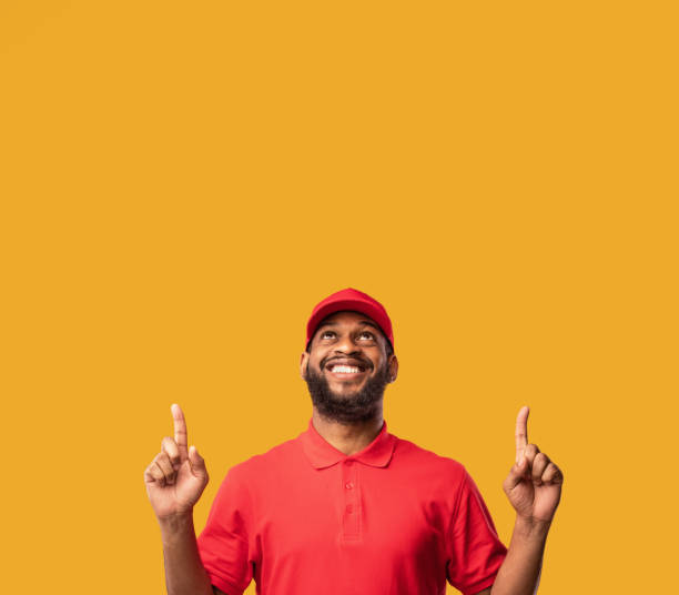 istock Courier Man Pointing Fingers Up At Free Space, Studio Shot 1224040991