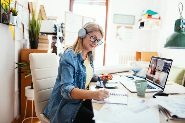 mujer de negocios madura trabajando de forma remota y teniendo videollamada con colegas - digital enhancement audio fotografías e imágenes de stock