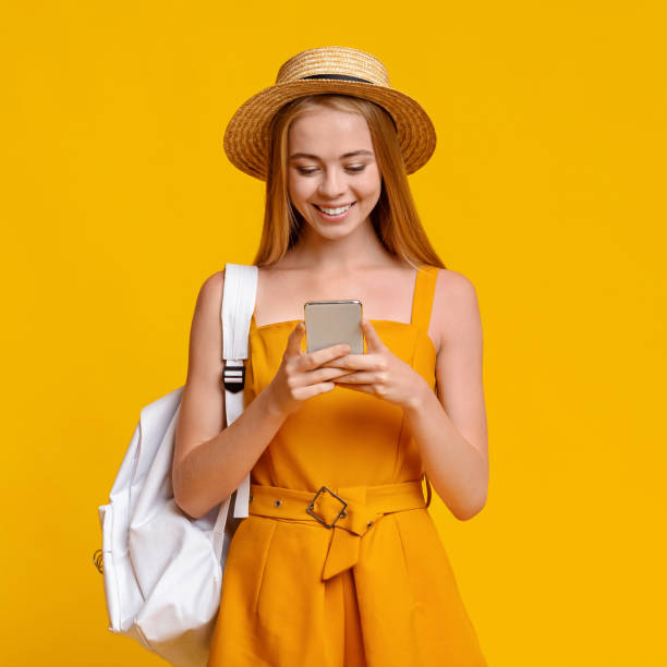 istock Travel Sim Concept. Girl Tourist With Backpack Using Smartphone Over Yellow Background 1224042373