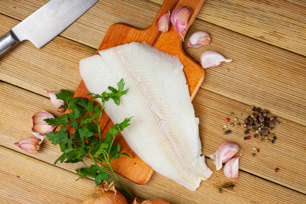 Raw halibut fillet with greens and spices Fresh raw halibut fillet with greens and spices on wooden background. Cooking ingredients turbot stock pictures, royalty-free photos & images