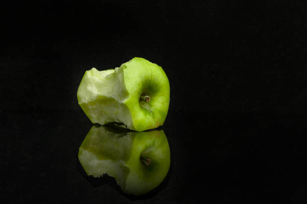 istock stub of a green apple with reflection on a black background. 1224047038