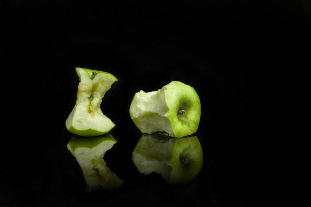istock bits of green apples with reflection on a black background. 1224047049