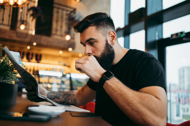 homme s’asseyant dans le bar de café - reading newspaper men magazine photos et images de collection