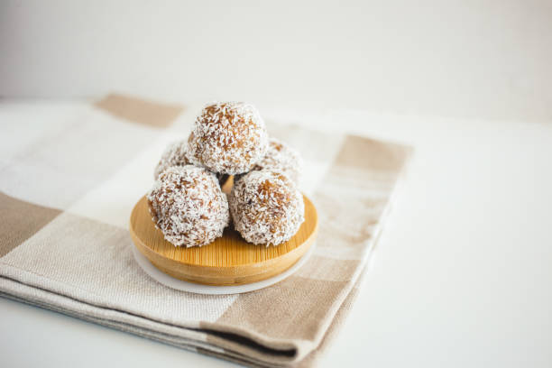 Energy balls of dates, peanuts, honey, almonds, coconuts on a light background, copy the space, lie flat. Healthy food, healthy snack. Raw dessert. Vegan vegetarian raw snack or meal.