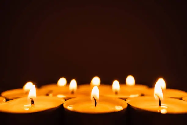 Burning candles in a row in the dark with copy space.