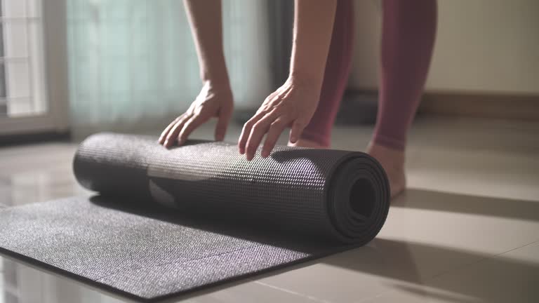 Women rolls her yoga exercise mat, getting prepared for practice