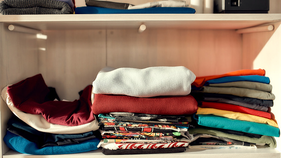 Clothes neatly folded on shelves. Stack of colorful clothing. Horizontal shot. Web Banner