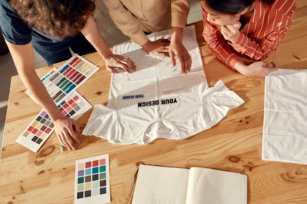 istock Writing for your success. Creative people trying on stickers with text, while discussing logo and design of T-shirt. Young man and women working together at custom T-shirt, clothing printing company 1224060134
