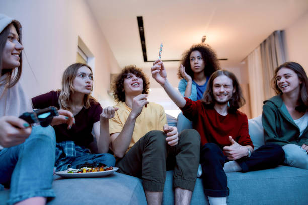 istock Young guy showing marijuana joint or hashish cigarette to his surprised friends while relaxing together on the coach at home 1224064896