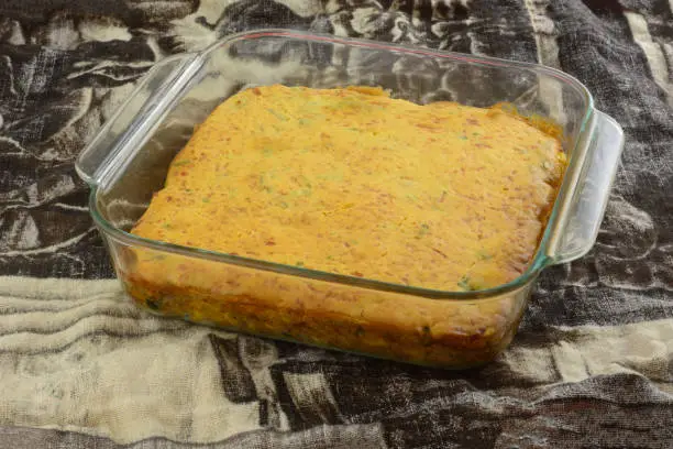 Cooked casserole with cheese cornbread crust topping in glass baking pan