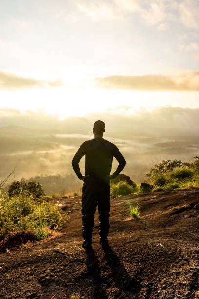 man backlight soaking the amazing view of mountain layers covered with white mist at dawn