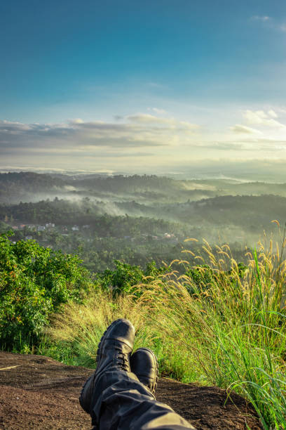 hiker resting at hilltop with breathtaking mountain layers in background hiker resting at hilltop with breathtaking mountain layers in background image is showing the human love towards the nature. kodaikanal photos stock pictures, royalty-free photos & images