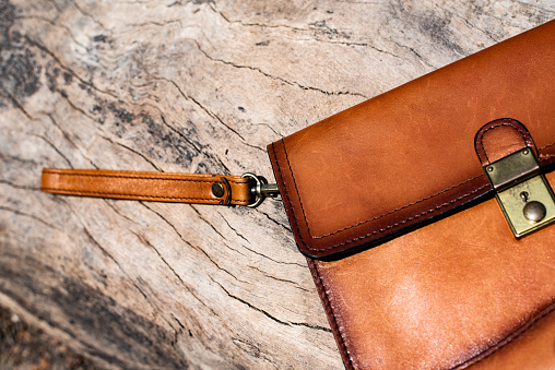 Close up brown leather wallet on wood texture.