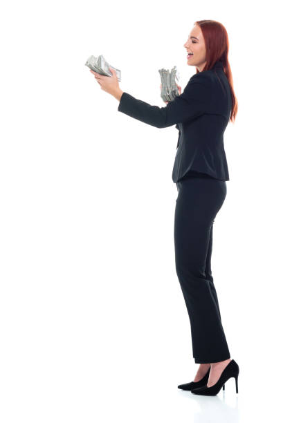 mujeres jóvenes caucásicas de negocios de pie frente a fondo blanco usando ropa de negocios y sosteniendo moneda - laughing women us paper currency isolated fotografías e imágenes de stock