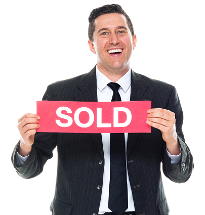 Front view of caucasian male business person standing in front of white background wearing businesswear who is cheerful and holding sign