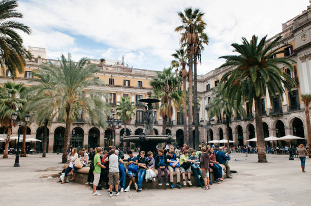 wielu młodych turystów siedzi pod słońcem i palmami na placua reial w pobliżu ulicy la rambla - barcelona - panoramic international landmark national landmark famous place zdjęcia i obrazy z banku zdjęć