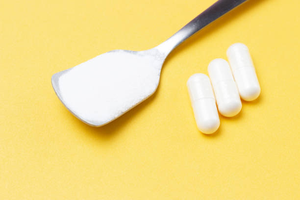 istock Collagen powder in a spoon and three white capsules on yellow background 1224083583