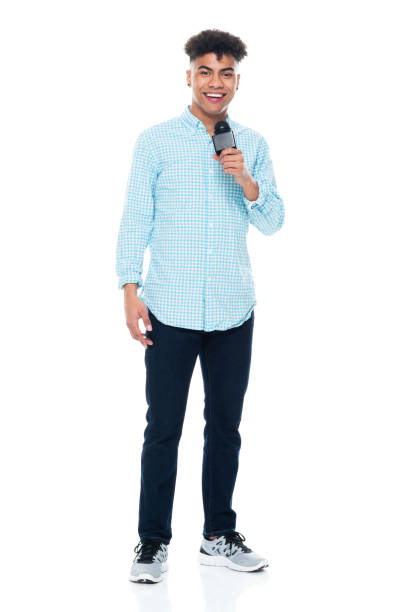Generation z male sportscaster standing in front of white background wearing shirt and holding microphone Full length of aged 18-19 years old with black hair generation z male sportscaster standing in front of white background wearing shirt who is showing cool attitude and holding microphone commentator photos stock pictures, royalty-free photos & images